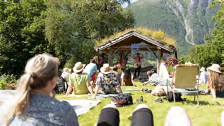 An outdoor grass-roofed stage at Bakketunet with an audience on the lawn.