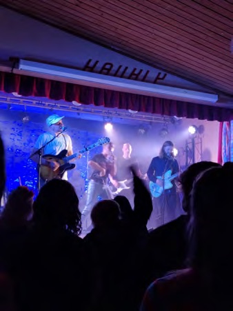 A band playing under stage lights on the Haukly stage.