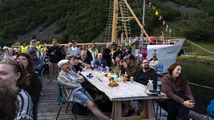 Festival-goers at a long table on the pier as the Polarstar docks behind them.